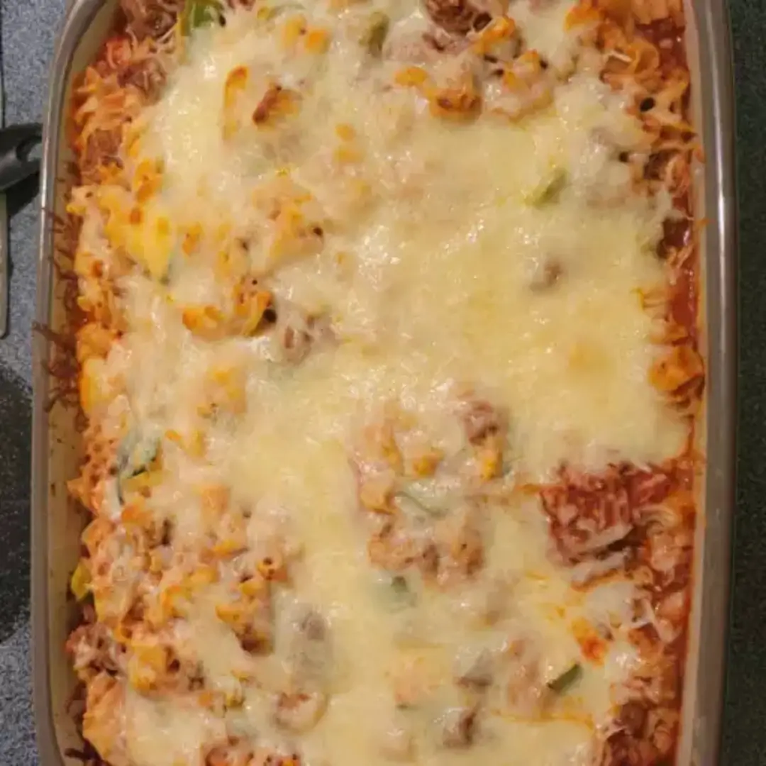 Baked pasta casserole with cheese and beef in white dish